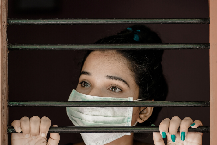 Lock down is my prison. Showing woman with medical mask behind bars