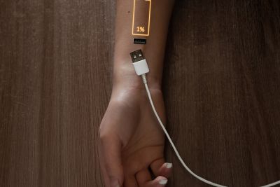 I challenge you to look back on the past and recharge your battery for less of the grindstone. Image shows an arm with a battery ready to recharge.